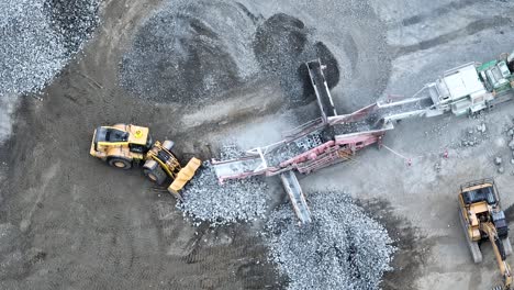 drone shot tracking mining bob cat truck as it collects rocks from conveyer belt