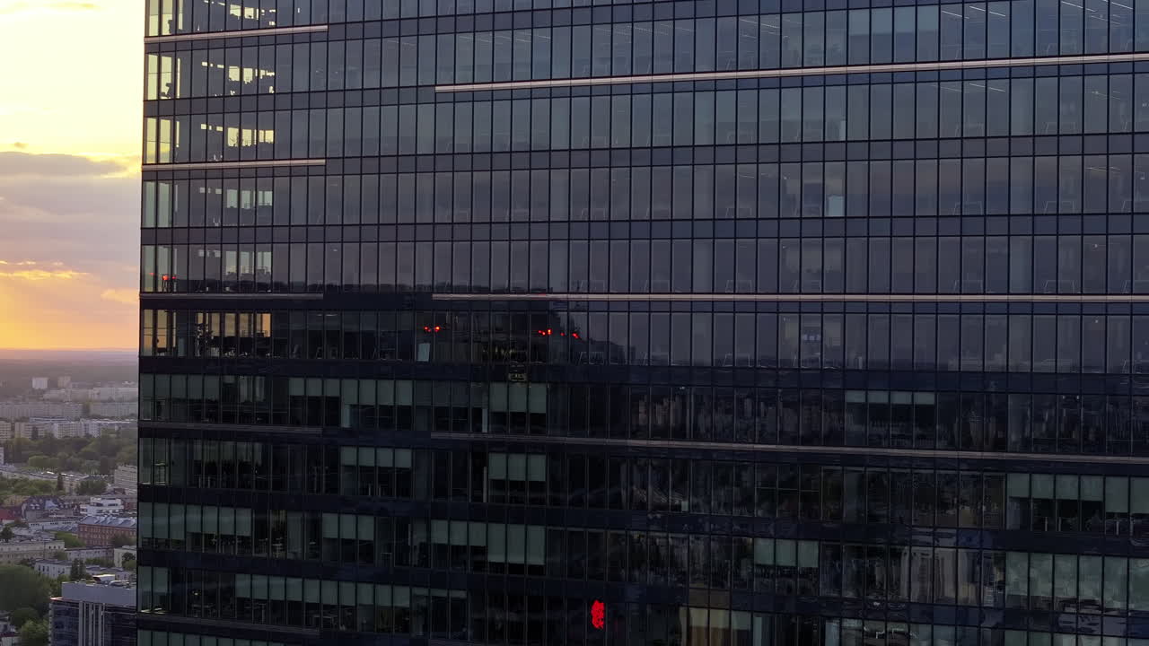 Warsaw, Poland - A Golden Sunset Casts a Warm Glow Over a Sleek Skyscraper, Reflecting the City's Modern Skyline - Aerial Drone Shot
