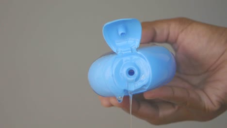 close up of a hand pouring blue liquid from a bottle