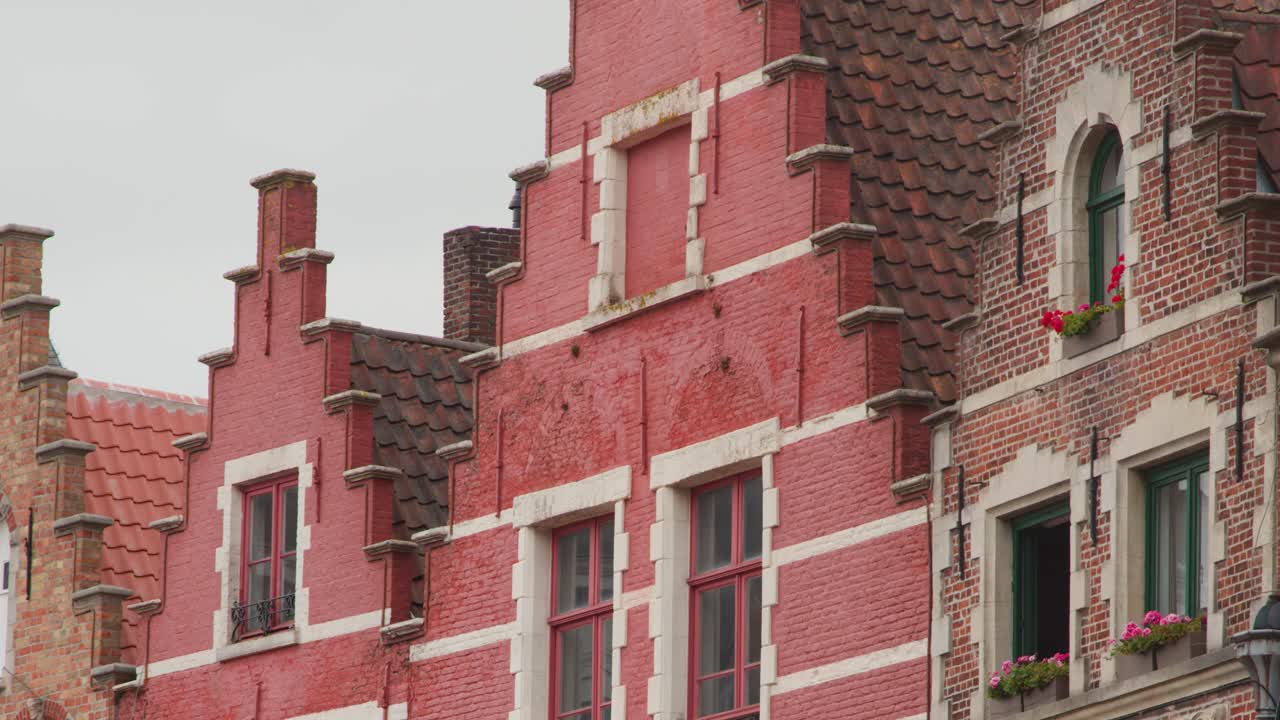 Camera slowly pans across ornate brick architecture, gabled roofs, and green windows in overcast daylight