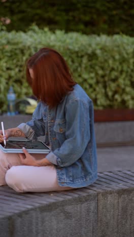 woman drawing on tablet outdoors