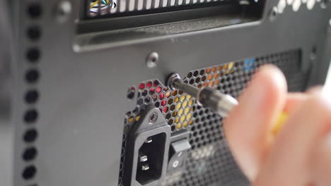 a computer repair technician assembling a new gaming pc case with a power supply and screw driver