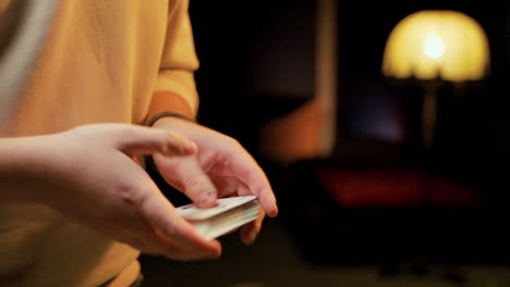 close up view of the hands of a man in a yellow t shirt shuffling poker cards