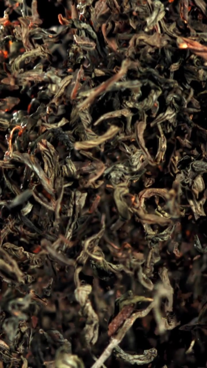 Dried Tea Leaves Falling in Slow Motion on Black Background