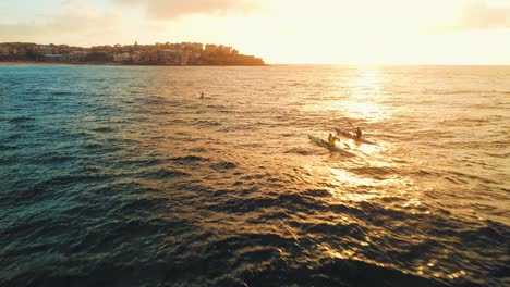 Toma-Aérea-De-Seguimiento-De-Algunos-Kayakistas-En-La-Playa-De-Bondi-Durante-El-Amanecer