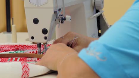 female worker hands sewing cross stitch fabric on weaving machine. fabric weave