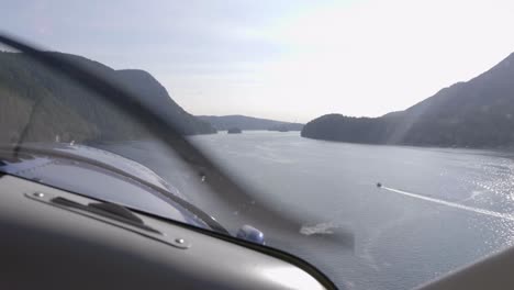 vista piloto volando bajo sobre un lago montañoso con un avión de hélice
