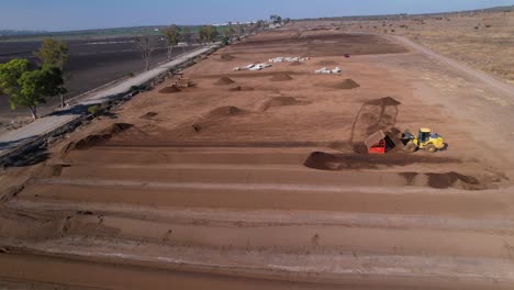 Low-aerial-pull-back-of-yellow-tractors-working-on-a-compost-farm-in-mexico