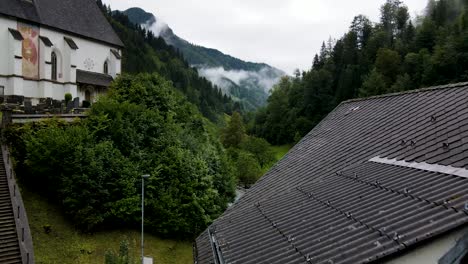 Slovenia-Small-Town-Surrounded-By-Misty-Pine-Forest-Mountains-Aerial-Drone-2