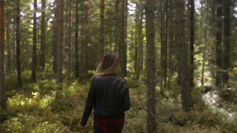 a woman wearing a leather jacket walks in a forest