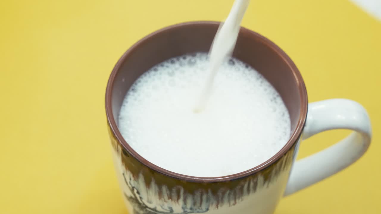 vertiendo leche caliente en la taza. toma de primer plano