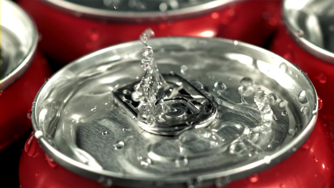 Gocce d'acqua che schizzano su una lattina di bibita rossa fredda al rallentatore