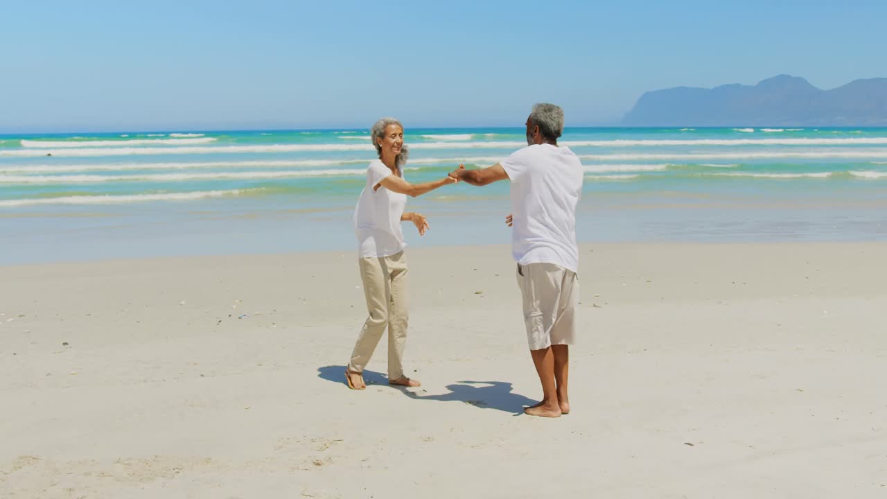해변에서 함께 춤추는 로맨틱한 활동적인 시니어 아프리카계 미국인 커플의 측면 전망 4k