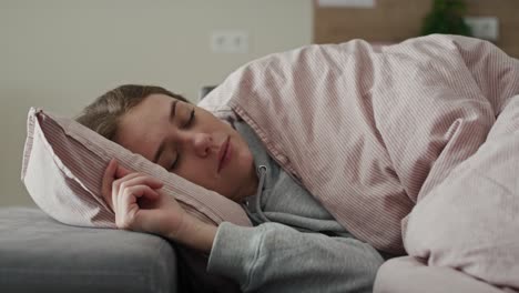 una mujer caucásica enferma durmiendo bajo el edredón.