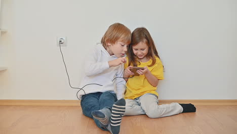 little girl and boy with a smartphone using an app and playing an online video game