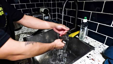 person washing dishes in a kitchen sink