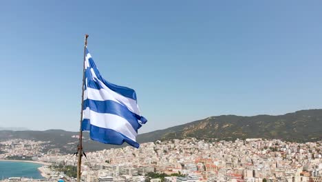 greek flag waving in slow motion, macedonia greece, aerial point of interest shot, aegean sea view