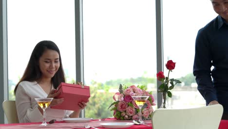 romantic couple giving gift to lover at restaurant