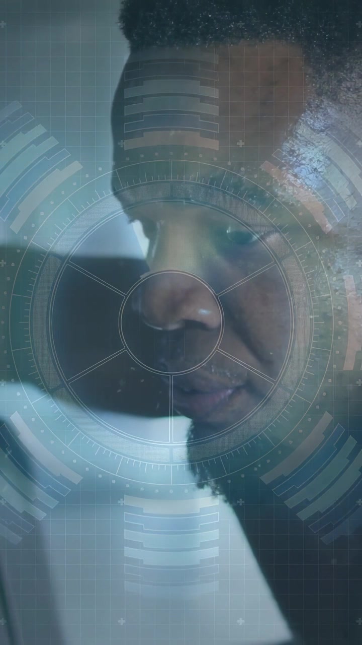 Vertical video: Adult man noticing device, leaning forward studying HUD data for technology readout