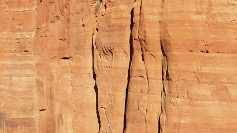 Formación-De-Arenisca-Pared-De-Montaña-Rocosa-A-La-Luz-Del-Sol-En-Sedona,-Arizona---Disparo-Inclinado-Hacia-Arriba-Disparo-De-Drone