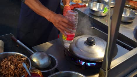 a street food vendor adding sauce into the wok, steaming the ingredients, cooking delicious three-cup stir-fry sizzles over roaring flames, close up shot.