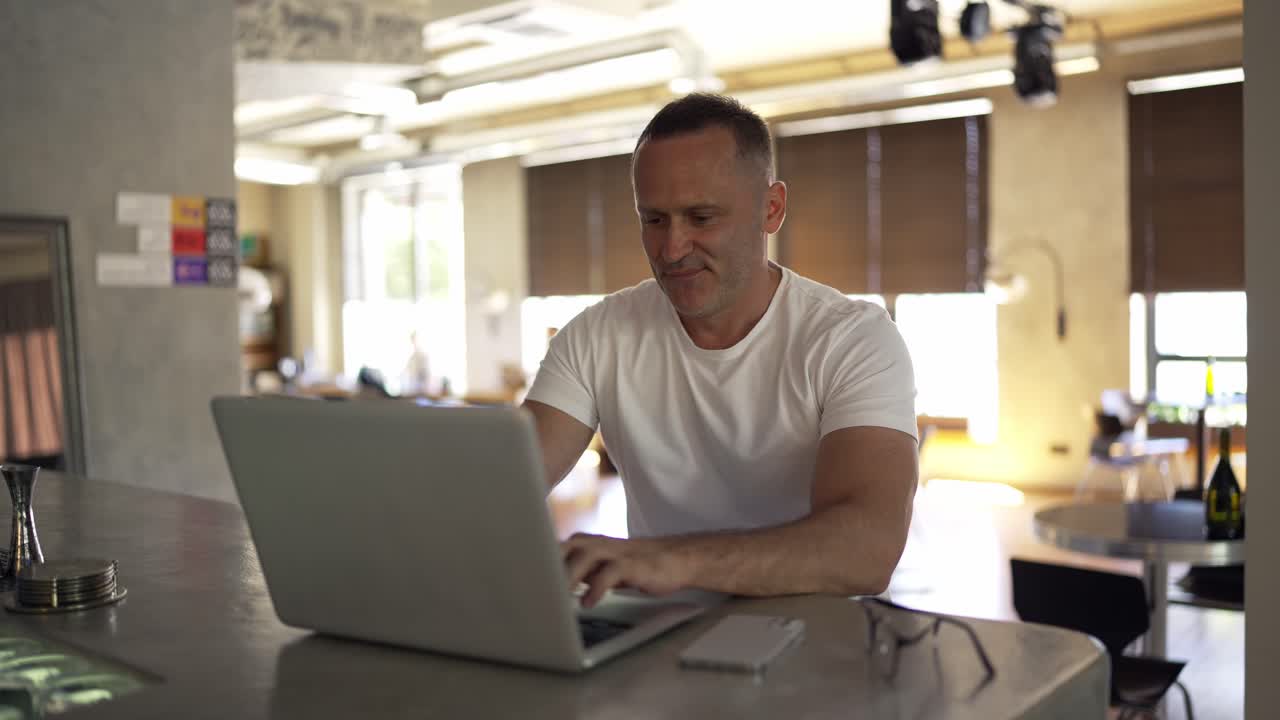 Smiling businessman working on laptop computer at home office. Male professional typing on laptop keyboard at office workplace