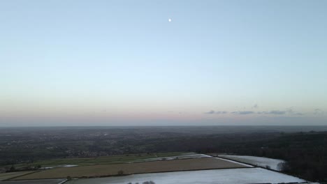 Una-Toma-De-Drones-Aéreos-De-4k-Que-Muestra-Una-Luna-Llena-Sobre-Un-Paisaje-Invernal-Después-Del-Atardecer