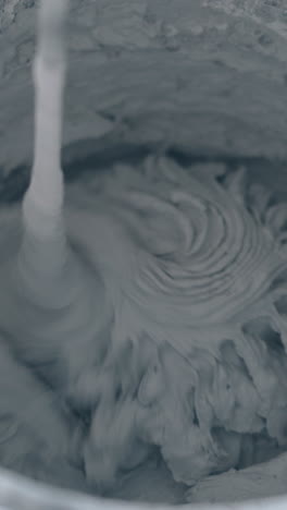 large plastic bucket with mixing grey putty prepared for smearing gypsum plasterboard wall constructions close view