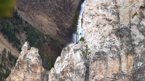 rock formations and a glimpse of the lower falls in the grand canyon of yellowstone