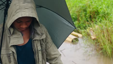 mid shot of a boy walking through marsh land on a rainy day