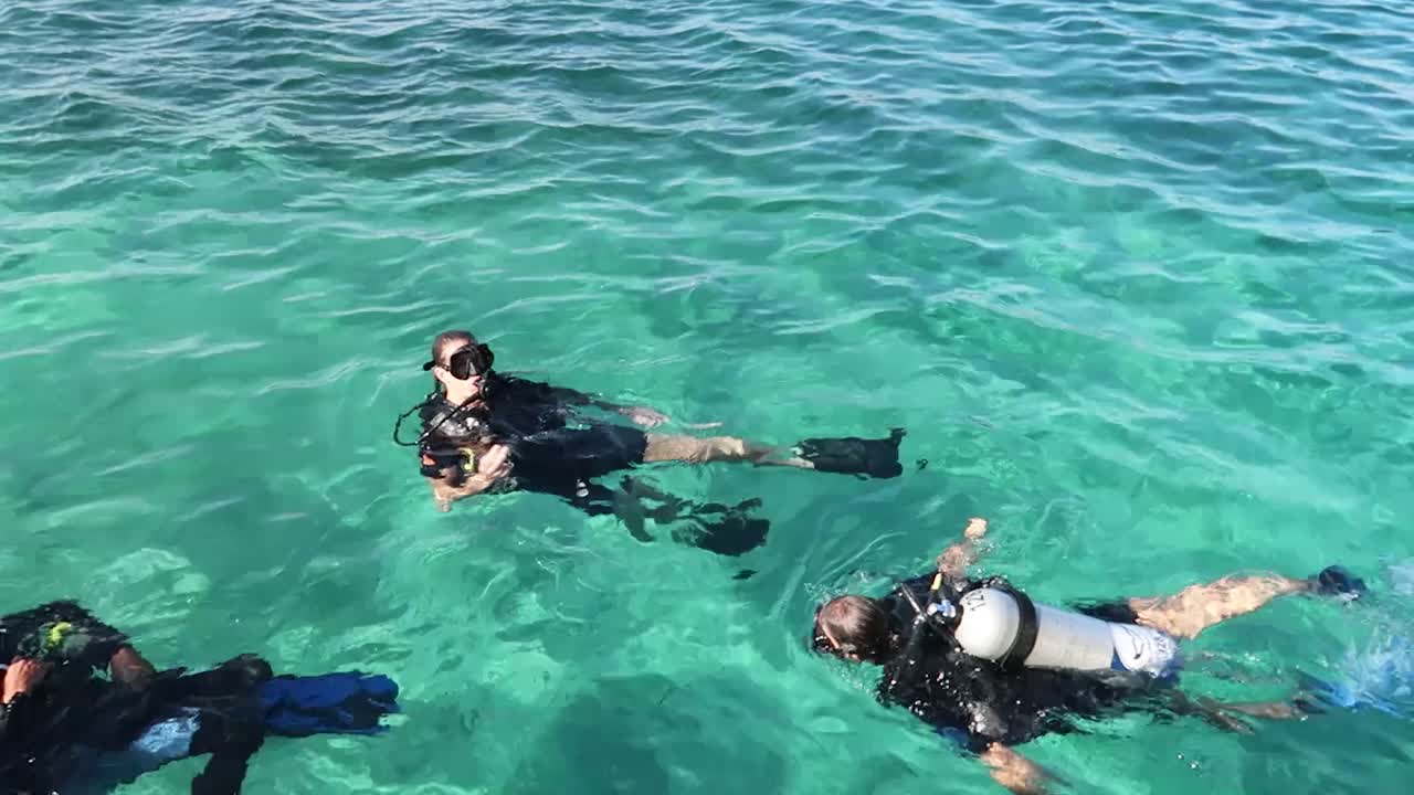 Three scuba divers preparing for a dive in the Mediterranean sea in Egypt.