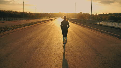 increíble disparo en cámara lenta con una deportista corriendo al atardecer o al amanecer una dama en ropa deportiva está corriendo