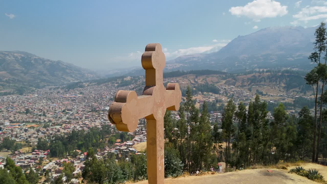 Large stone cross at Rataquenua viewpoint, revealing panoramic views of Huaraz city and the Andes mountains - Slow aerial parallax