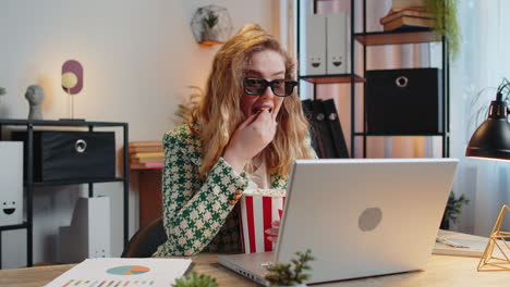 businesswoman taking break from work wearing 3d glasses eating popcorn and watching movie at office