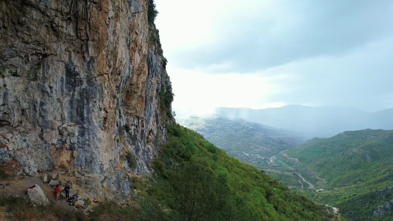 Side view (pan, tilt) of a natural rock cliff in Krrabë, near Tirana, perfect for climbing. Dynamic shot captures the immense wall and green valley, conveying outdoor adventure in the Balkans