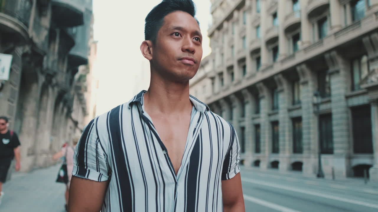 Man in Striped Shirt Walking on City Street