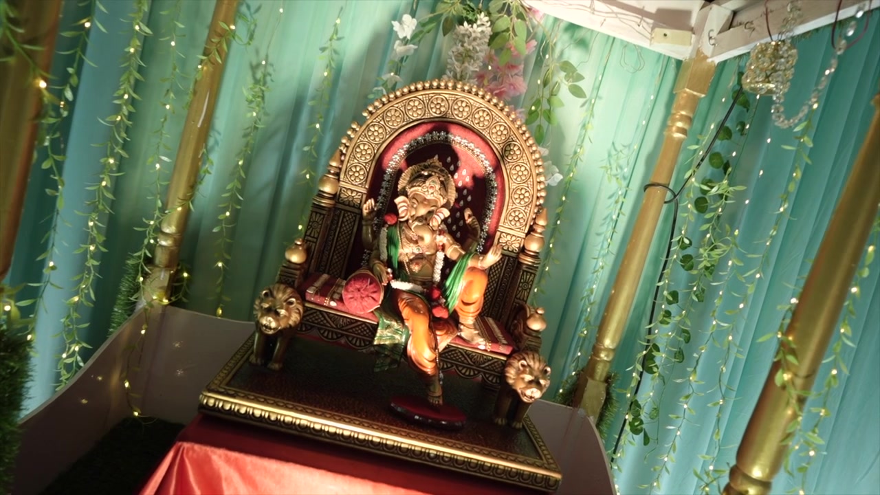 Ângulo dinâmico de uma estátua dourada do Senhor Ganesha repousando sobre um mandap de casamento ornamentado, irradiando bênçãos divinas, prosperidade, elegância e significado espiritual.