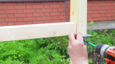 The worker screws the metal corner to the board with a screwdriver. Construction. close-up.