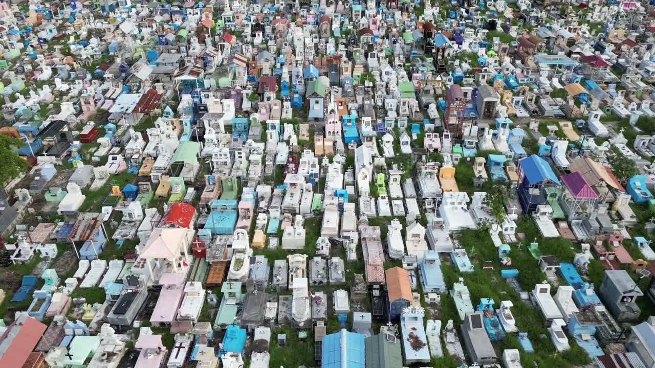 Drone flies from afar towards colorful tombs in a cemetery in Dili, Timor-Leste