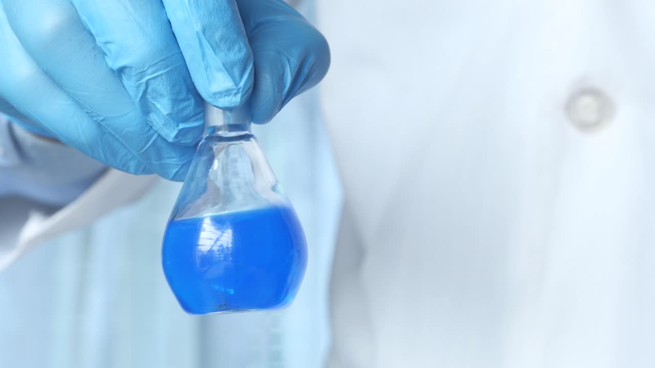 científico sosteniendo un frasco lleno de líquido azul