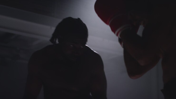 Close Up Shot Of Two Male Boxers Wearing Gloves In Boxing Ring Fighting In Boxing Match With Low Key Lighting 1