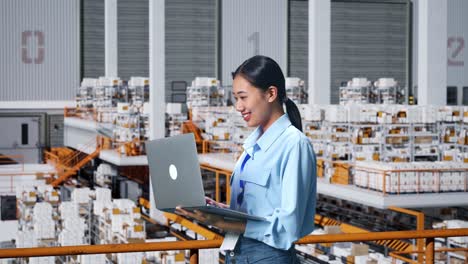 side view of asian business woman using laptop computer in the warehouse