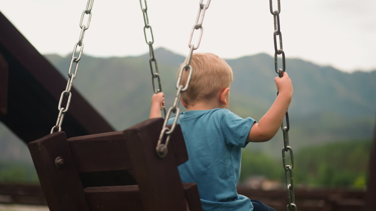 un niño pequeño juega con columpios hechos a mano contra grandes montañas