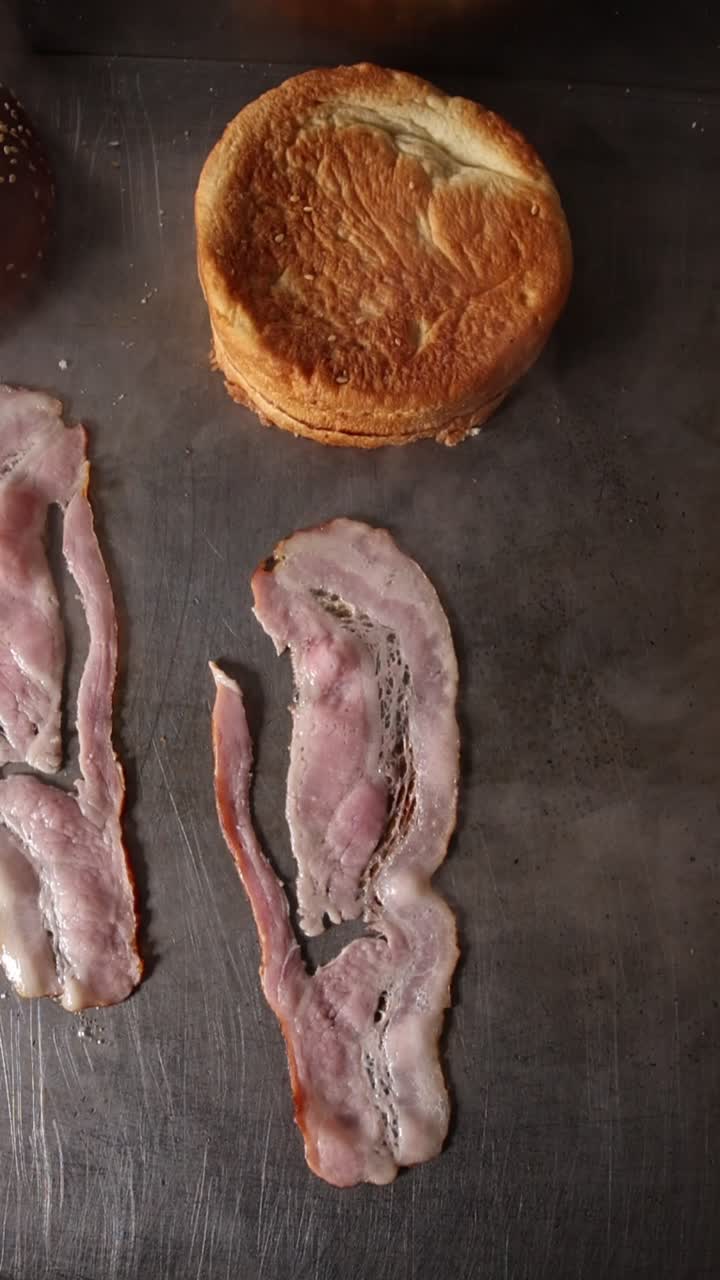 Pancetta e panino per hamburger cotti su una piastra calda