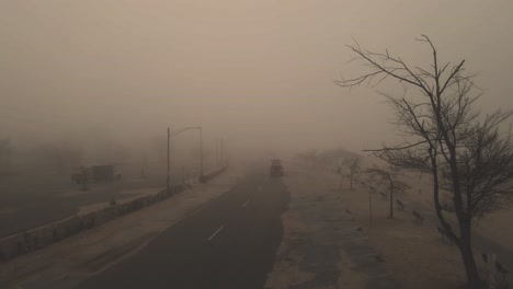 Descending-over-a-spooky-and-sandy-street,-fog-blurring-visibility