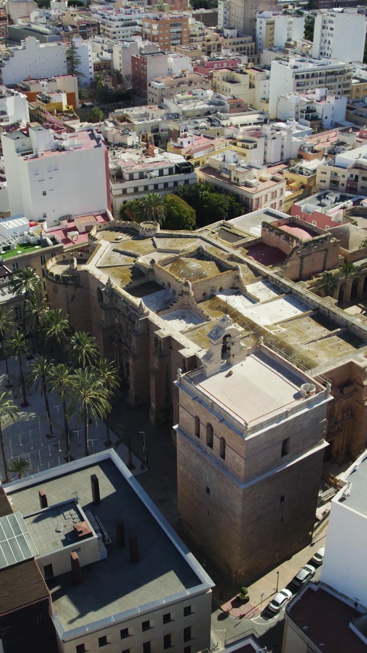 Drone footage performing a smooth orbit around Almería Cathedral, highlighting the historic architecture and urban surroundings.