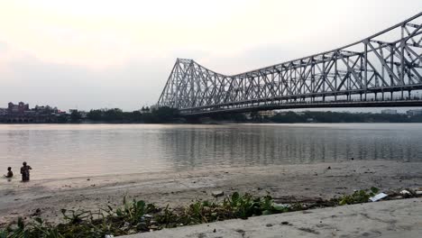 kolkata : motion timelapse of the beautiful howrah bridge along with old vintage boats passing beneath it.