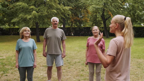 female fitness coach speaking to senior people in park