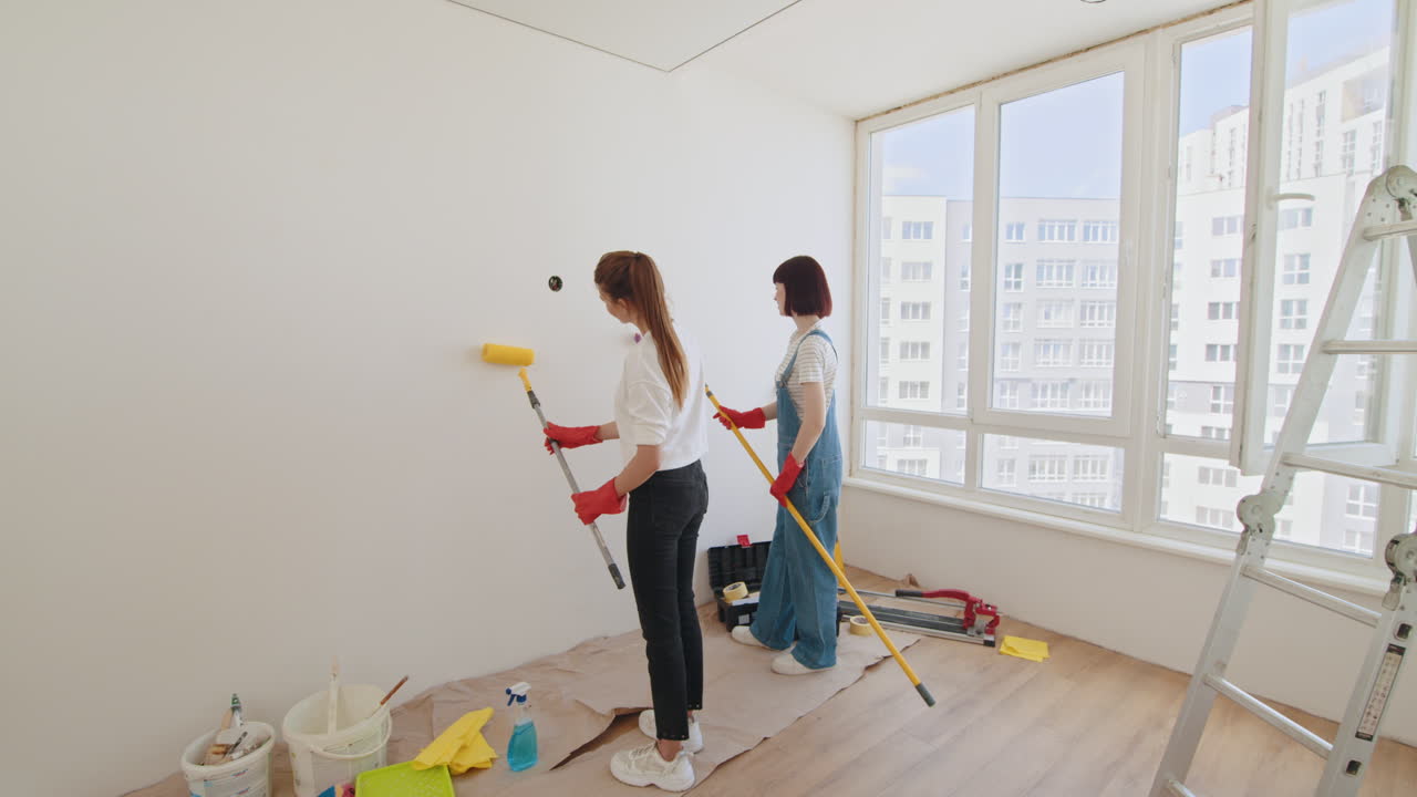 mujeres pintando una pared en una habitación