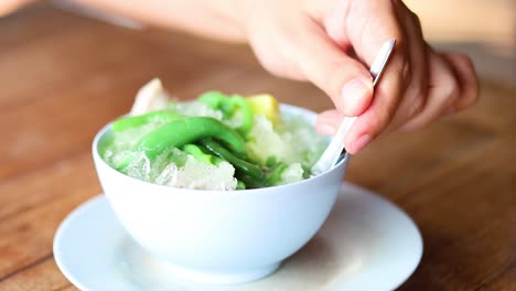 hands assembling a bowl of green shaved ice